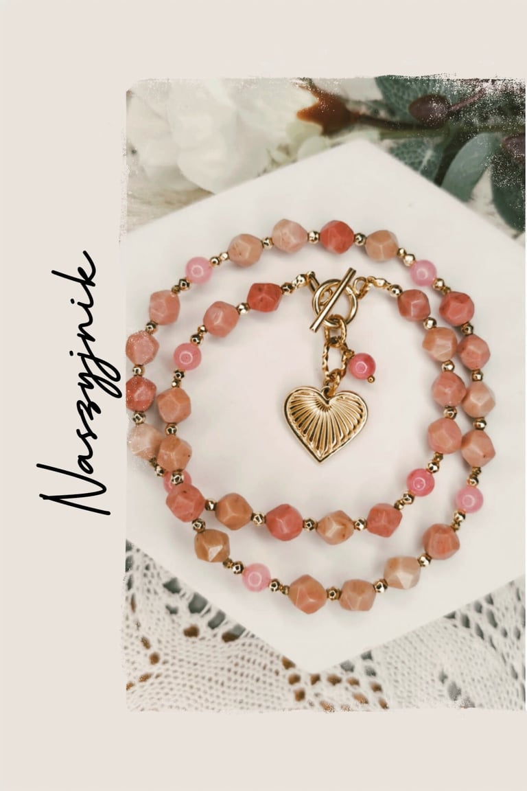 Beaded bracelet with pink and coral gemstones, gold spacers, and gold heart charm on white display card labeled Nusriyah