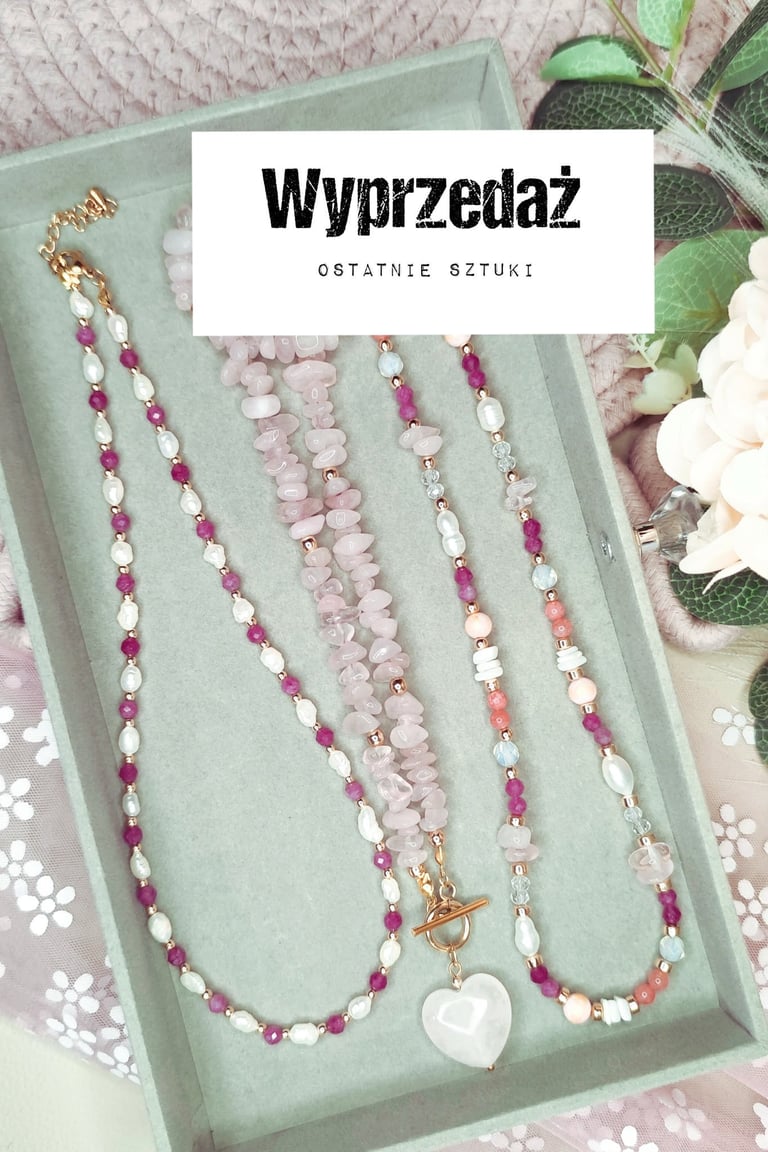 Multiple beaded necklaces with pink and white pearls displayed on a mint green tray with decorative plants and flowers nearby