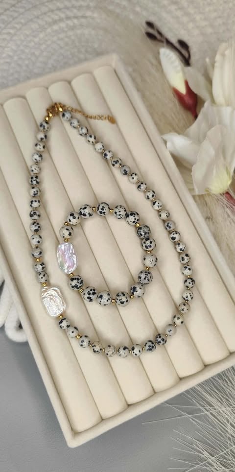 Beaded jewelry layered on white display stand with fresh white flowers in background