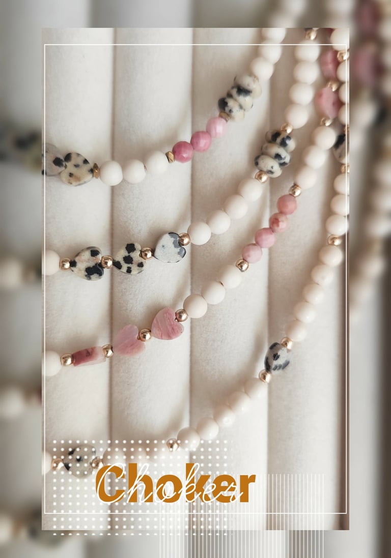 Collection of beaded chokers displayed on cream fabric with pink, white, and leopard print beads with gold accents